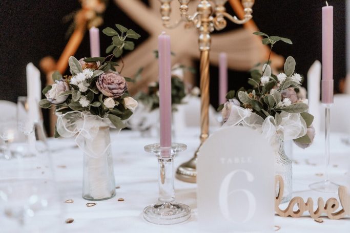 Tischdekoration mit Blumensträußen, Kerzen und einer „6 love“ Tafel.